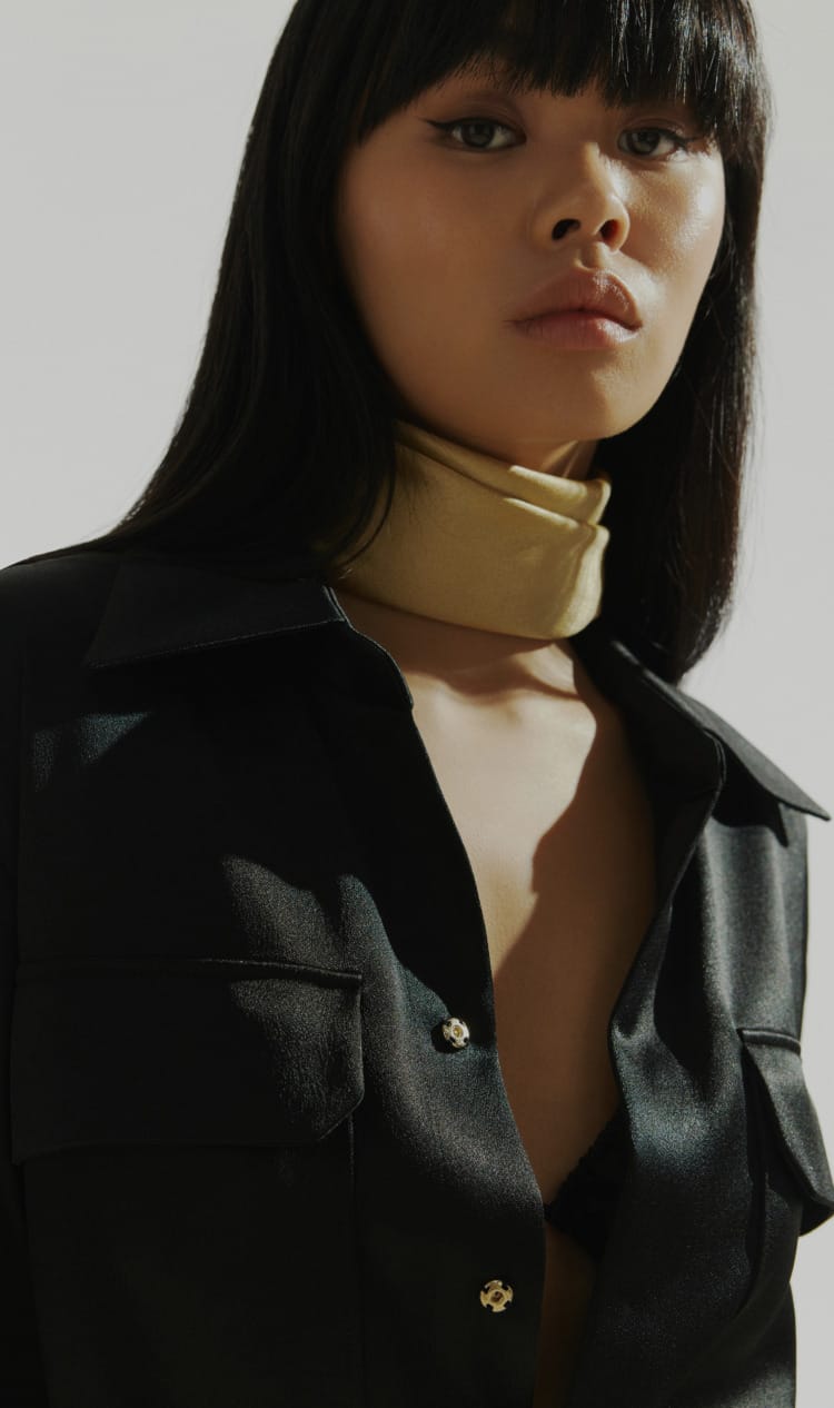 Fam Buro fashion model in a black outfit with a gold scarf